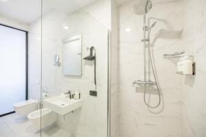 a white bathroom with a shower and a sink at Brosse Garden in Tbilisi City