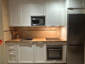 a kitchen with white cabinets and a microwave at Tramuntana & Beach in Pollença +18 photos