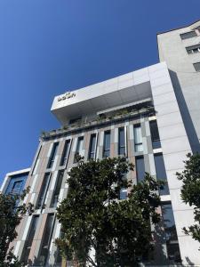 a tall white building with trees in front of it at Eden Center Rooms in Durrës