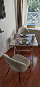 a wooden table with two chairs and a table with plates at Douglas in Colleville-sur-Mer