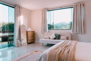 a bedroom with a bed and a couch and windows at Chalé Refúgio Fegama in Passa Quatro