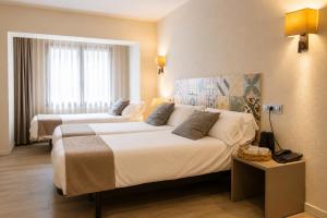 a hotel room with two beds and a window at Tudel in Andorra la Vella