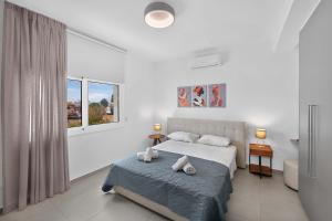 a white bedroom with a bed and a window at Sun & Moon Luxury - Celeste Villa in Ayia Napa +10 photos