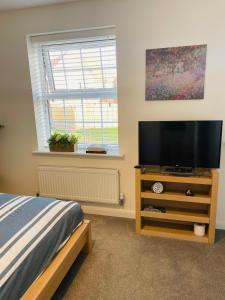 a bedroom with a flat screen tv on a dresser at Rushes View Homestay in Market Harborough