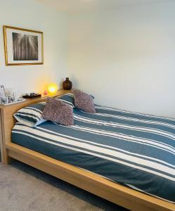 a bed with blue and white striped sheets and pillows at Rushes View Homestay in Market Harborough