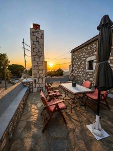 a patio with a table and chairs and an umbrella at Diaks Tower Sunset Sea View Mani in Pyrgos Dirou
