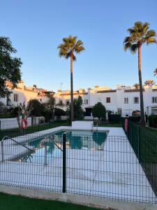 a swimming pool with palm trees and buildings at Casita Andaluza in San Luis de Sabinillas