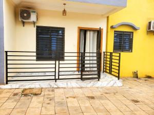a yellow house with black shutters and a balcony at At Home Bertoua in Bertoua