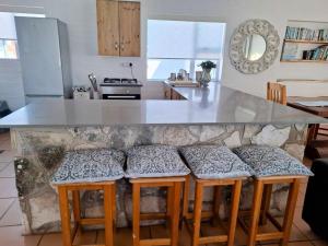 a kitchen with a counter with four stools at Lieflappie Seaview Stilbaai 400m to the beach in Stilbaai