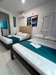 a hotel room with two beds with green sheets at Hotel Rodadero Suites By SGH in Santa Marta