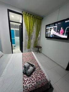 a bedroom with a bed with a tv on the wall at Hotel Rodadero Suites By SGH in Santa Marta