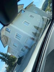 a white building is reflected in the rear view mirror of a car at 2 Schlafzimmer Apartment Bergland 