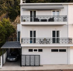 a white building with a car parked in front of it at Among the pines in Katakolo +11 photos