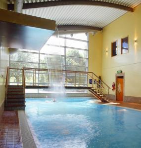 a swimming pool with a waterfall in a building at Apollo Hotel in Basingstoke