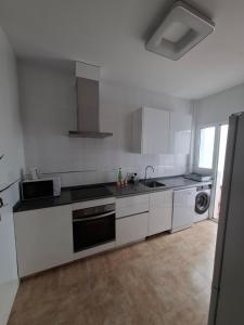 a kitchen with white cabinets and black counter tops at Casa turística AZAHAR in Villablanca