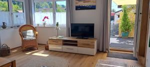 a living room with a flat screen tv and a chair at Eichkobel-Blick in Grünenbach