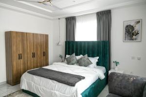 a bedroom with a large bed with a green headboard at Sunrise Cave in Oyibi