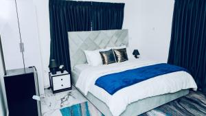 a bedroom with a large bed with blue and white sheets at Sunrise Cave in Oyibi