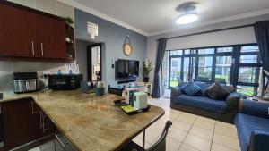a kitchen and living room with a blue couch at Topanga 17 in Uvongo Beach