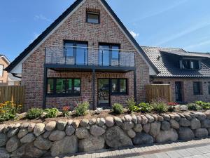 a brick house with a stone retaining wall at BeachHus 35, Whg 4 in Sankt Peter-Ording