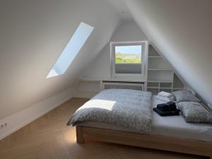 a bedroom with a bed and a window in a attic at BeachHus 35, Whg 4 in Sankt Peter-Ording