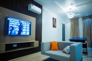 a living room with a couch and a tv on a wall at BBB Luxury Apartment in Amuwo