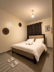 a bedroom with a bed with white sheets and slippers at Stylish Ngong Retreat with Balcony & Rooftop Lounge The Moon Stays in Ngong