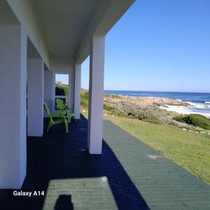a porch with a green chair and the ocean at ROMANZA APARTMeNT in De Kelders