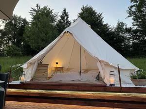 a white tent with a bed in a field at Vrhnika hill in Vrhnika
