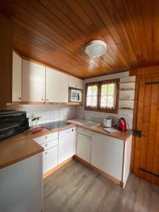a kitchen with white cabinets and a wooden ceiling at Le Mazot in Veyrier-du-Lac