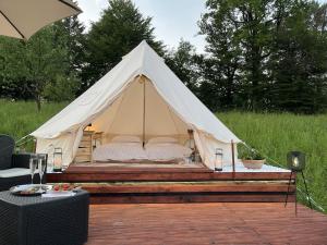 a white tent with a bed in a field at Vrhnika hill in Vrhnika
