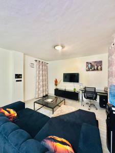 a living room with a blue couch and a tv at Stylish Ngong Retreat with Balcony & Rooftop Lounge The Moon Stays in Ngong