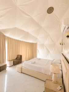 a white bedroom with a bed and a ceiling at RUM NADINE LUXURY CAMP & Bubbles Hotel in Wadi Rum