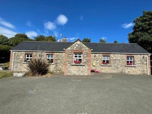 a stone house with red flowers in the windows at Cottage in the Dublin mountain in Dublin