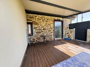 a patio with a table and chairs and a stone wall at Ribeira do Forno 2 in Adaúfe