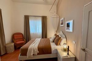 a bedroom with a bed and a window with a chair at Casa M&B in Las Galeras