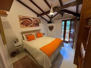 a bedroom with a bed with orange pillows on it at Chalé Guararema in Petrópolis +88 photos