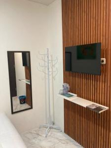 a room with a tv and a mirror on a wall at Hotel Sanrina Kuta Bali in Kuta