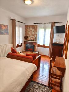 a bedroom with a bed and a living room with a fireplace at pasithea mountain rooms in Fylaktí
