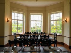 a dining room with a large table and windows at Graystone Bungalow by Seven Angels in Haputale