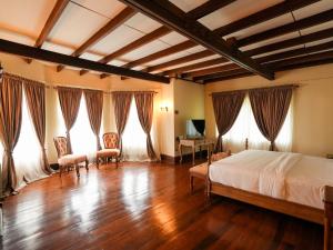 a bedroom with a bed and wooden floors and windows at Graystone Bungalow by Seven Angels in Haputale