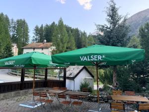 a green umbrella and some tables and chairs at Hotel Alp Sur in Mühlen +14 photos