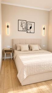 a white bedroom with a large bed and a table at Студия ЖК "Кенесары" in Kokshetau