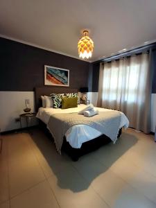 a bedroom with a large bed and a chandelier at Sea Spray Table View Beachfront Bliss in Cape Town