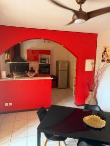 a kitchen with red walls and a black table at Villa Boat red in Quartier Morne Acajou