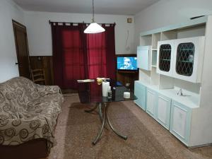 a living room with a table and a chair and a television at Monte Grande Hostel in Monte Grande