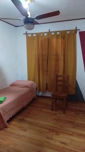 a bedroom with a bed and a chair and a ceiling fan at Monte Grande Hostel in Monte Grande