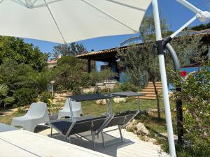 a table and chairs under an umbrella on a deck at La Casa del Vento Plemmirio in Plemmirio