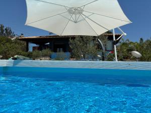 a white umbrella sitting next to a swimming pool at La Casa del Vento Plemmirio in Plemmirio