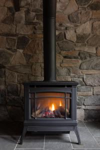 a fireplace with a fire in a stone wall at Hotevilla A-Frame Cabin with Wi-Fi & Pine Tree Views in Flagstaff +38 photos